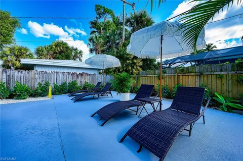 a view of a patio with couches table and chairs under an umbrella with a small yard