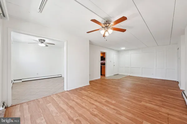 an empty room with chandelier fan and wooden floor