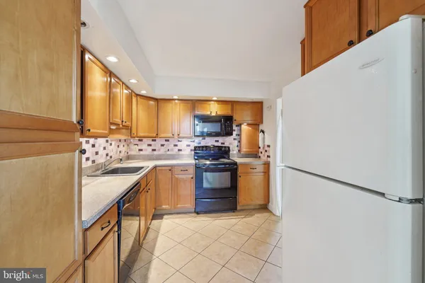 a kitchen with stainless steel appliances granite countertop a refrigerator sink stove and oven