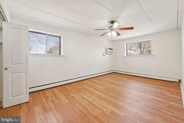an empty room with wooden floor ceiling fan and windows