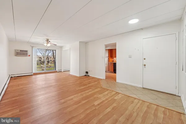 a view of an empty room with window and wooden floor