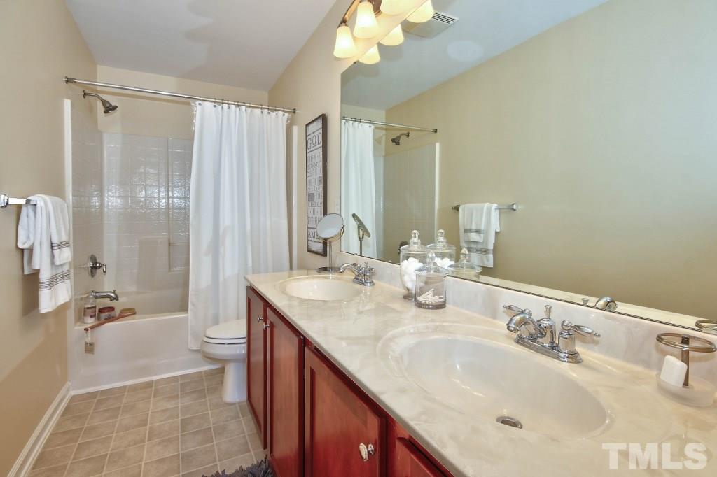4225 Hopper Street Raleigh, NC 27616 - Photo 16 of 19 a bathroom with double vanity sinks a toilet a mirror and shower
