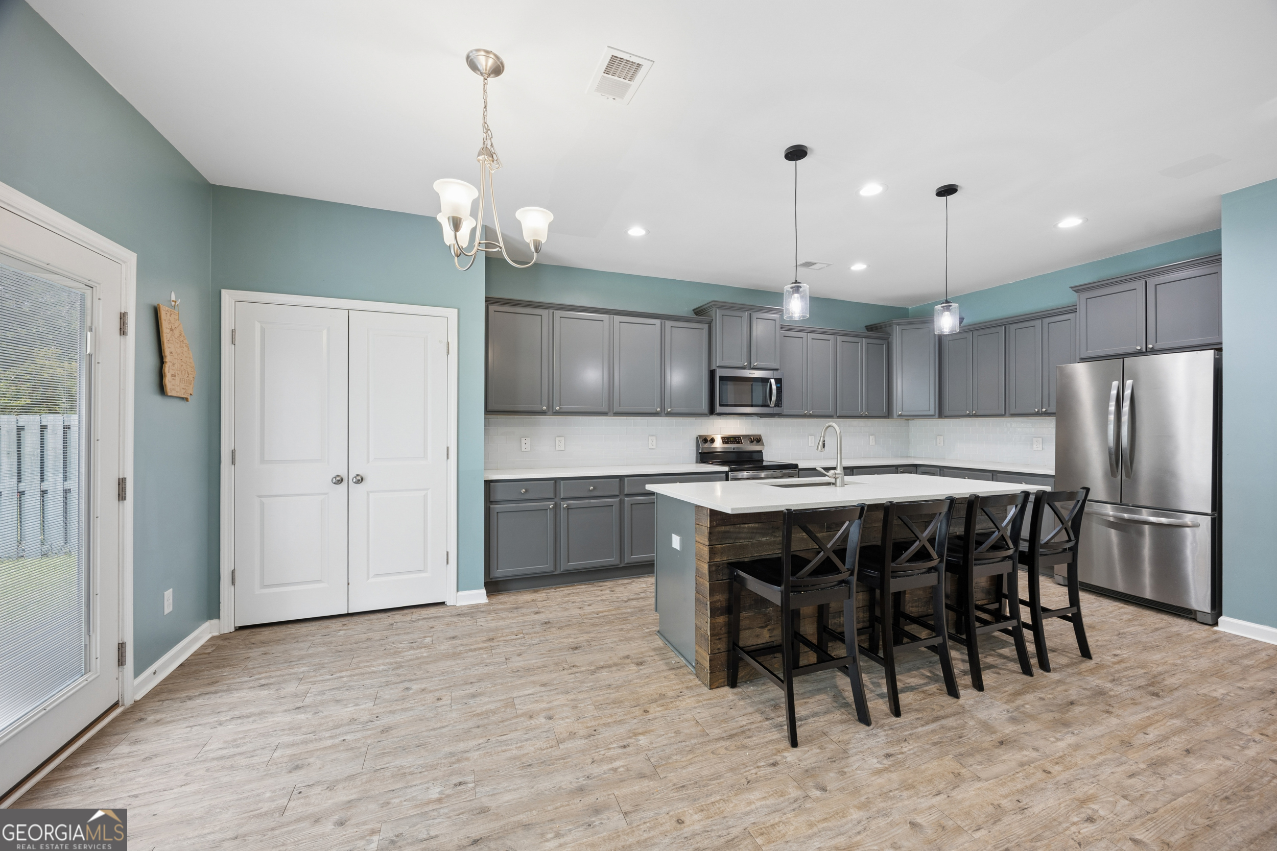 369 Waybridge Way Richmond Hill, GA 31324 - Photo 15 of 40 a kitchen with kitchen island granite countertop a sink cabinets a refrigerator and chairs