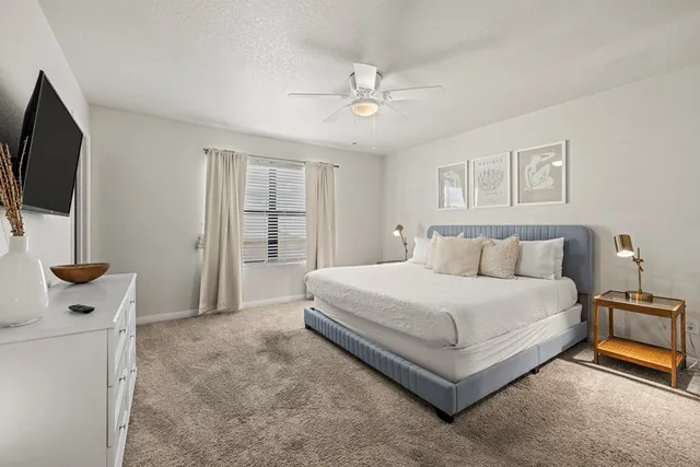 a spacious bedroom with a bed and a flat screen tv