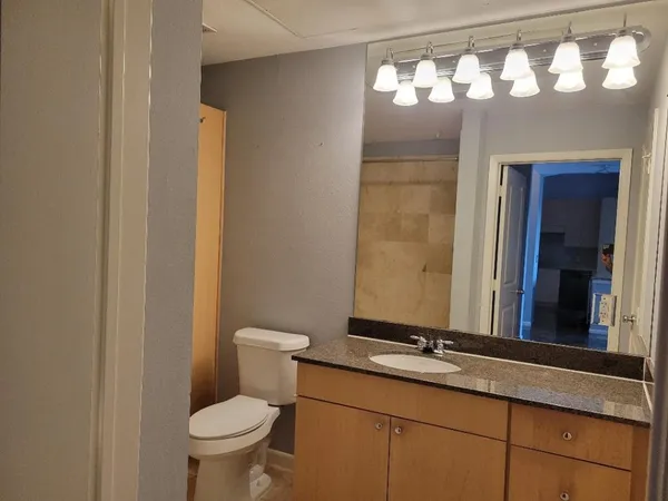 a bathroom with a granite countertop sink mirror vanity and toilet