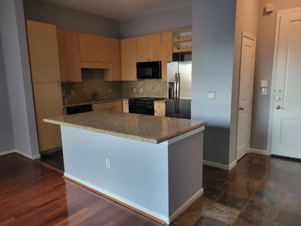 a kitchen with granite countertop a refrigerator and a stove top oven
