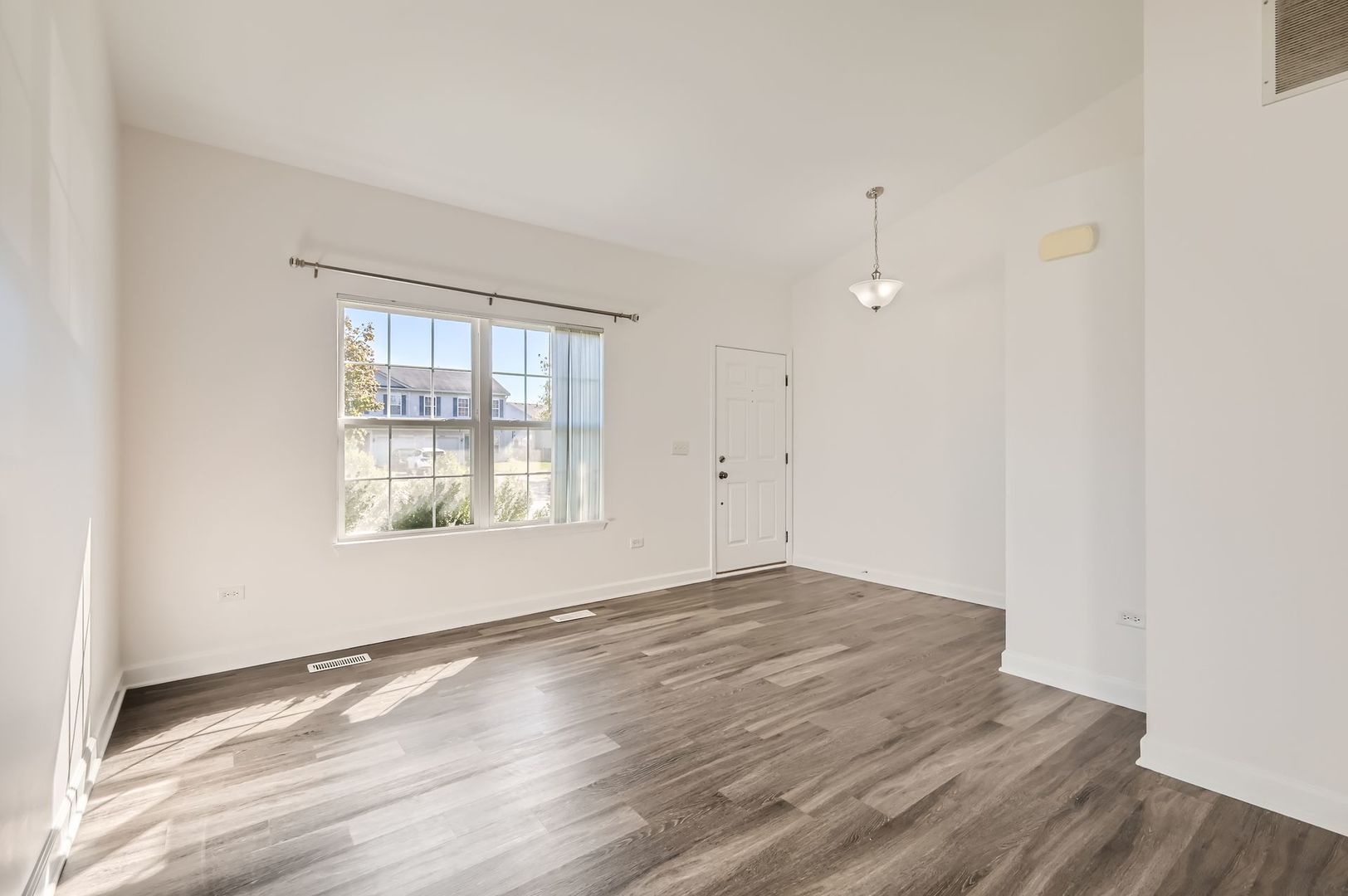 3019 Hoffman Street Plano, IL 60545 - Photo 2 of 10 an empty room with wooden floor and windows