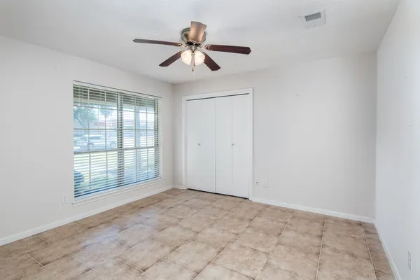 an empty room with chandelier fan and windows