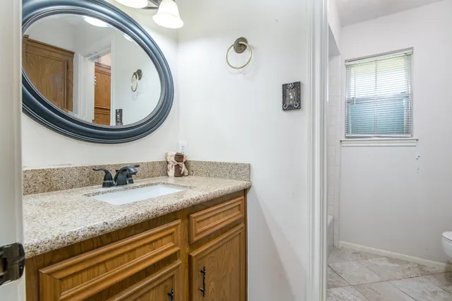a bathroom with a granite countertop double vanity sink and a mirror