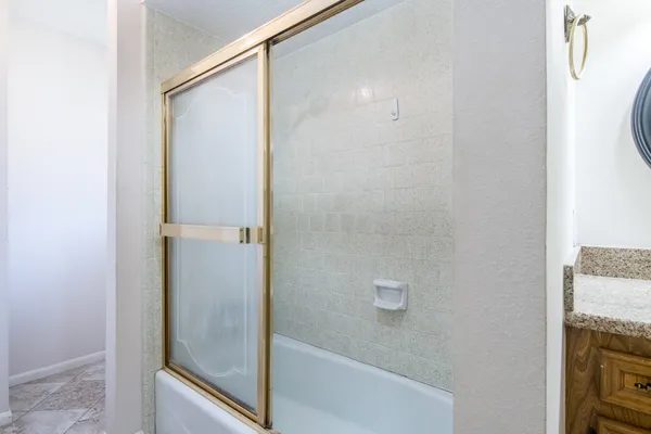 a bathroom with a granite countertop shower and a sink