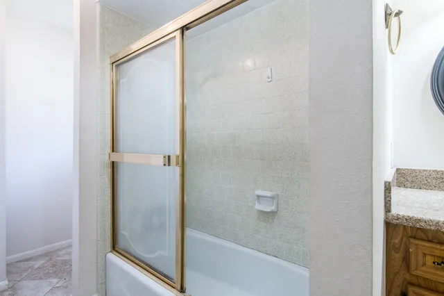 a bathroom with a granite countertop shower and a sink