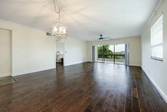 a view of a room with wooden floor chandelier and windows