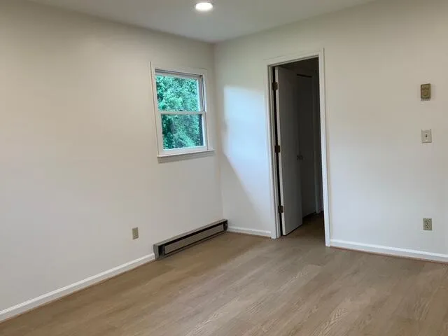 an empty room with wooden floor and windows