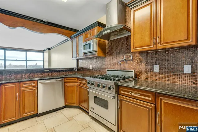 a kitchen with stainless steel appliances granite countertop a stove a sink and a microwave