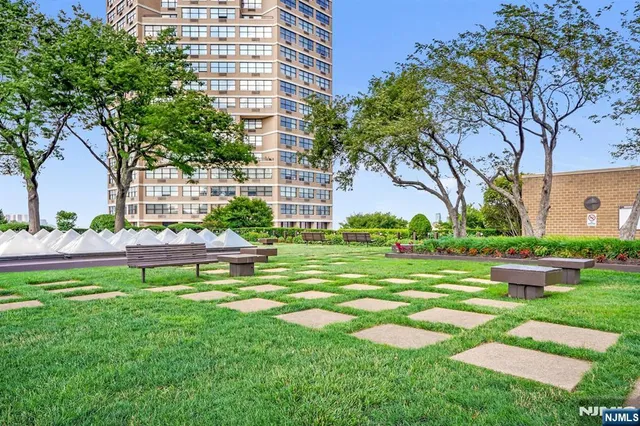 a front view of a house with garden and a bench