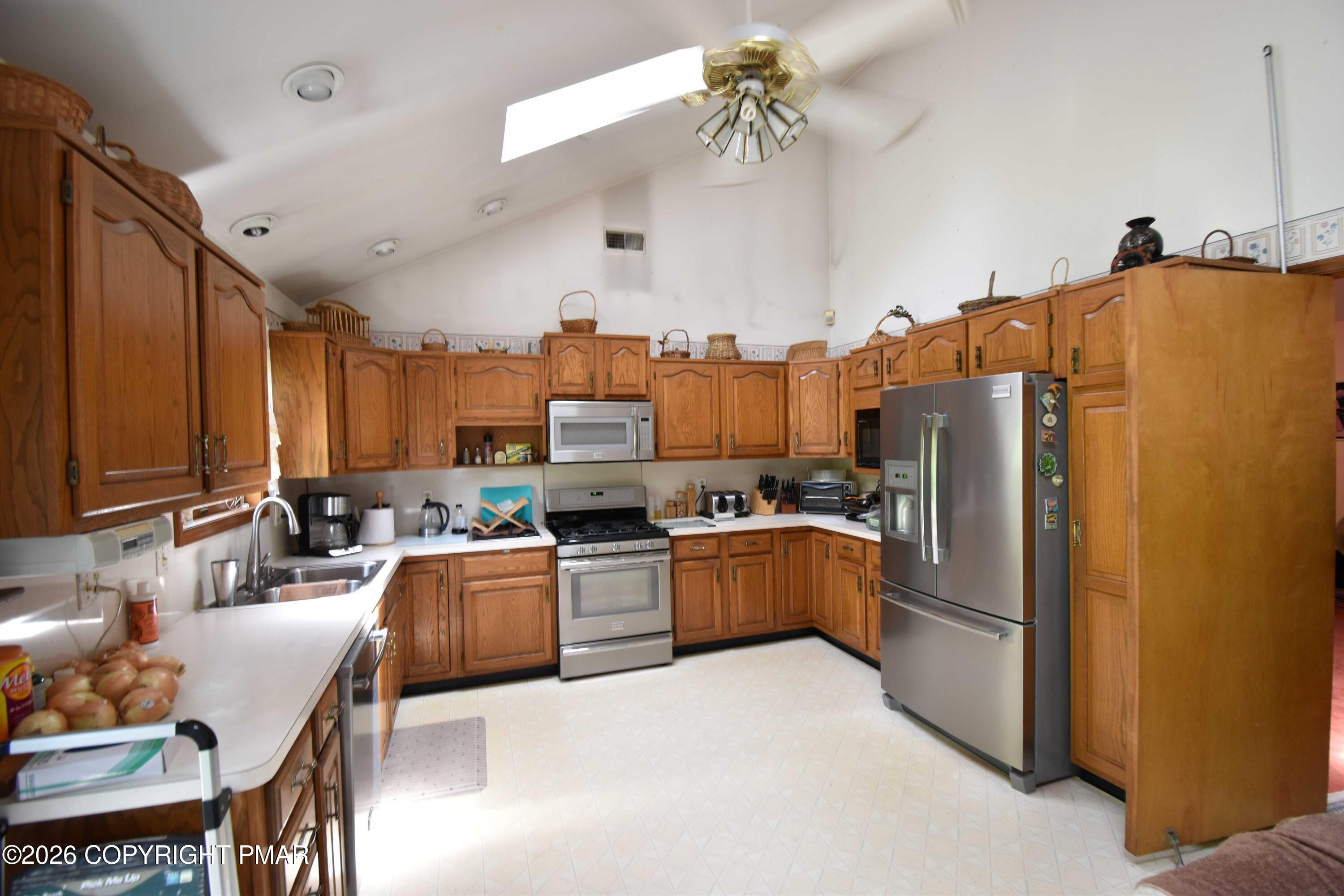 160 Quiet Valley Road Mount Bethel, PA 18343 - Photo 19 of 44 a kitchen with stainless steel appliances a refrigerator a stove a sink dishwasher a dining table and chairs with wooden floor