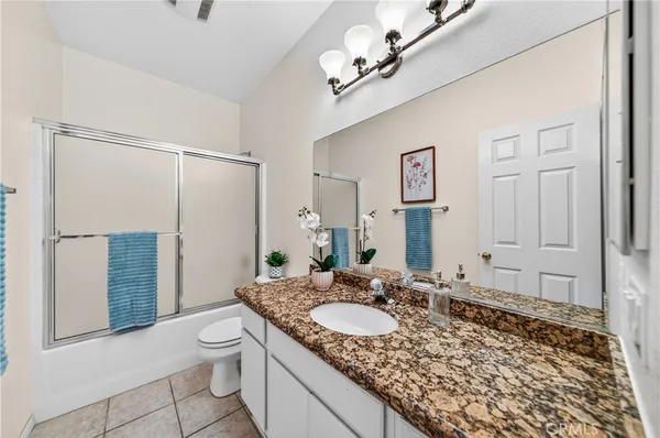 a bathroom with a granite countertop sink a toilet a mirror and shower