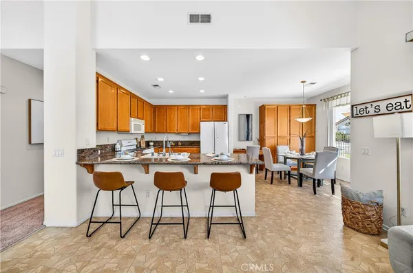 a kitchen with stainless steel appliances granite countertop table chairs sink and cabinets