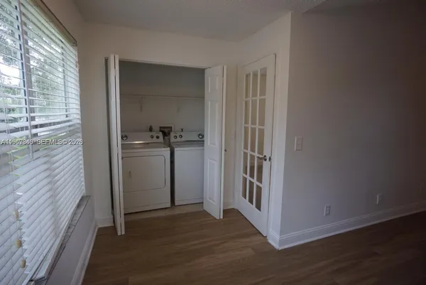 a view of a hallway with wooden floor and a bathroom