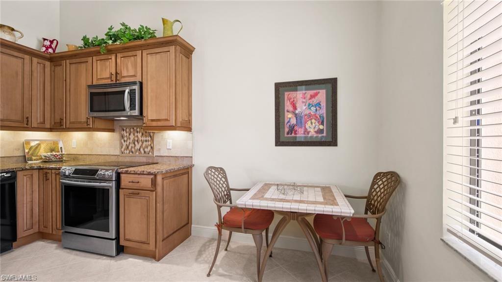 577 Beachwalk Circle, Unit R202 Naples, FL 34108 - Photo 13 of 44 Kitchen with stainless steel appliances, light stone countertops, wood finish cabinetry, and light tile patterned floors