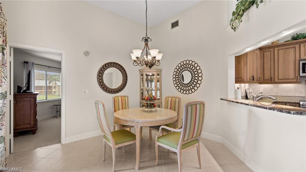 577 Beachwalk Circle, Unit R202 Naples, FL 34108 - Photo 14 of 44 Dining room with suspended lighting, light tile patterned floors, and vaulted ceiling