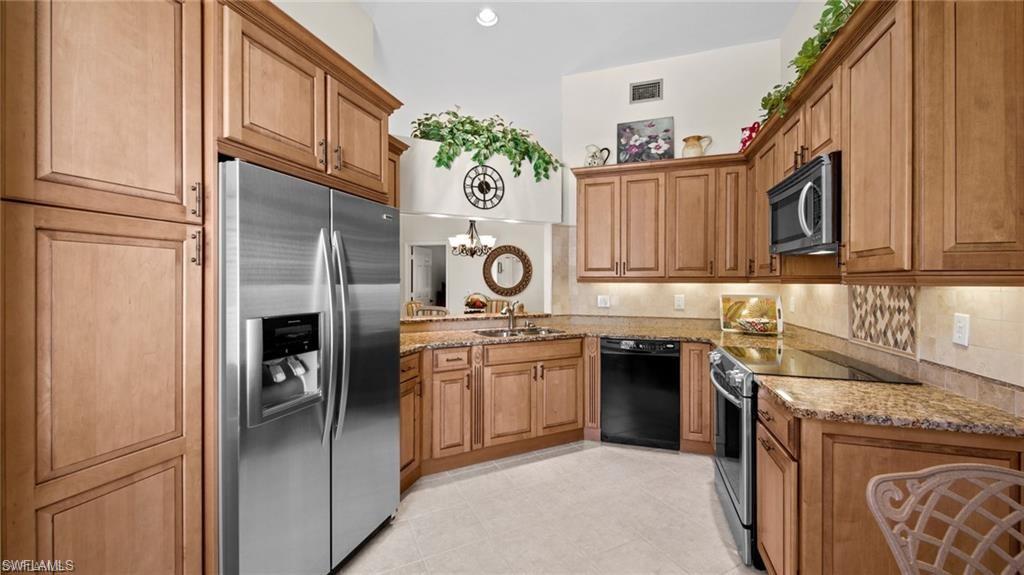 577 Beachwalk Circle, Unit R202 Naples, FL 34108 - Photo 8 of 44 Kitchen with stainless steel appliances, light stone countertops, wood finish cabinets, and hanging lights