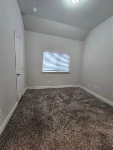 an empty room with chandelier fan and windows