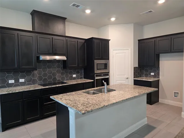 a large kitchen with kitchen island a sink stainless steel appliances and cabinets