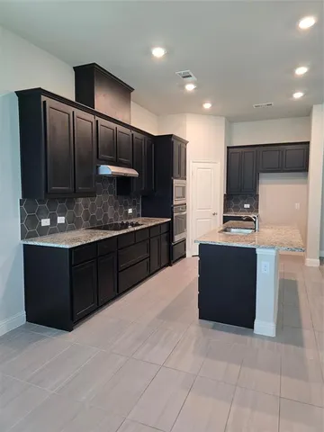 a kitchen with kitchen island granite countertop wooden cabinets and a refrigerator