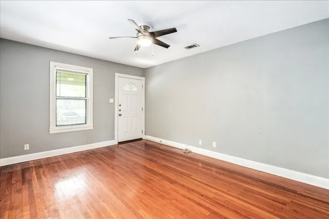 a view of an empty room with wooden floor and a window
