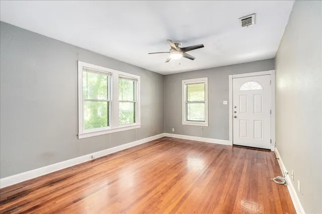 a view of empty room with wooden floor and fan