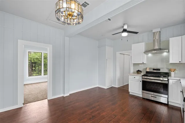 an empty room with wooden floor a ceiling fan and windows