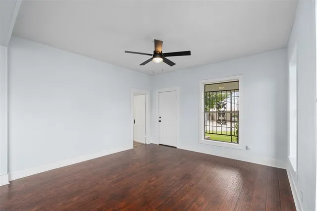 an empty room with windows and a ceiling fan