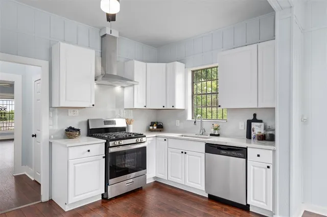 a kitchen with cabinets stainless steel appliances a sink and wooden floor