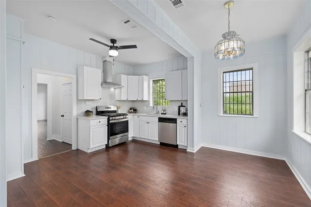 a kitchen with granite countertop a stove a sink and dishwasher with white walls