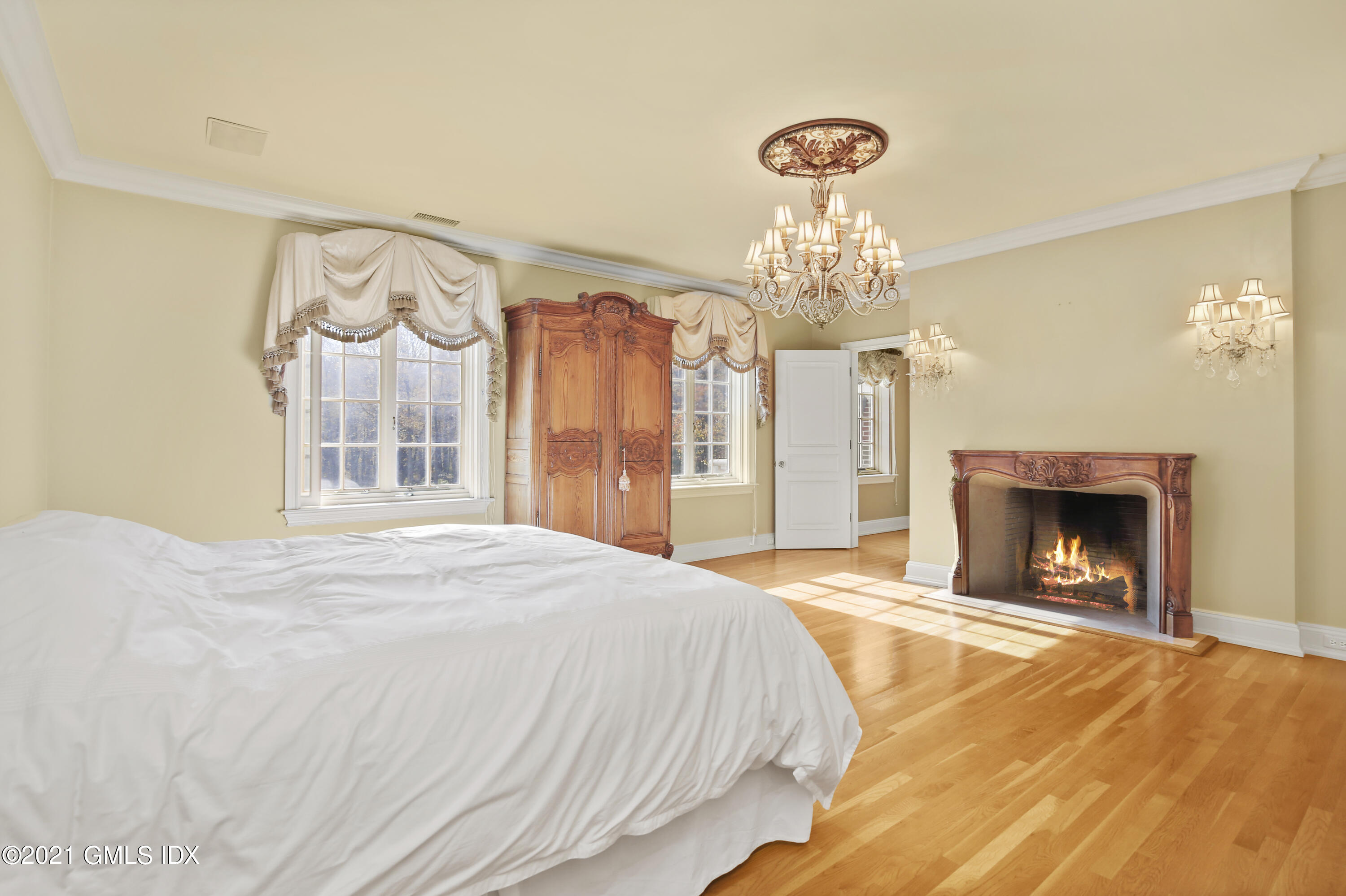 18 Lower Cross Road Greenwich, CT 06831 - Photo 23 of 40 a spacious bedroom with a bed and a chandelier