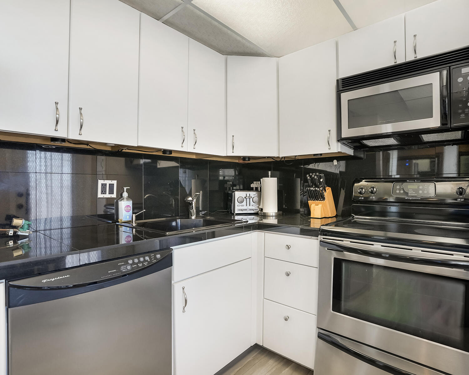 2671 South Course Drive, Unit 907 Pompano Beach, FL 33069 - Photo 2 of 21 a kitchen with granite countertop white cabinets stainless steel appliances and a sink