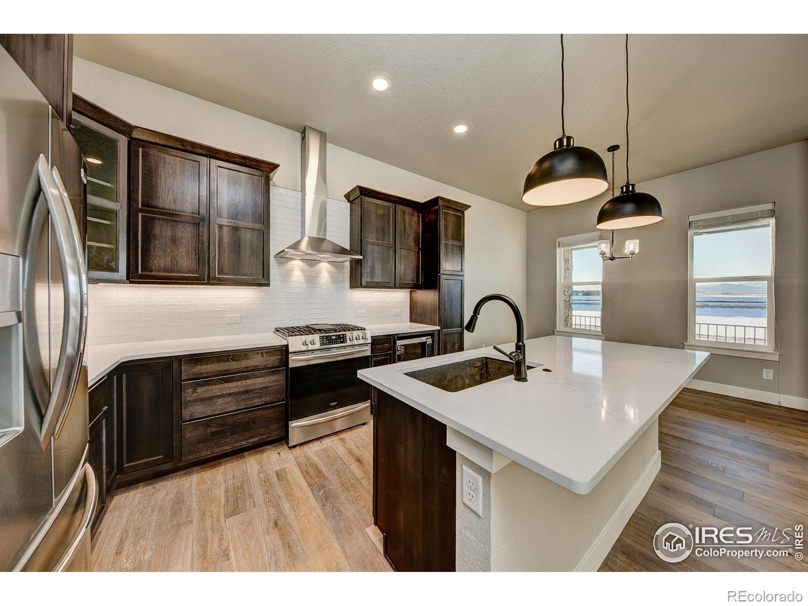 6227 Vernazza Way, Unit 4 Windsor, CO 80550 - Photo 1 of 15 a kitchen with stainless steel appliances granite countertop a sink a stove and a wooden floors
