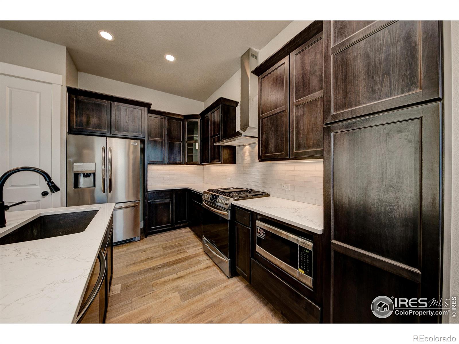 6227 Vernazza Way, Unit 4 Windsor, CO 80550 - Photo 2 of 15 a kitchen with stainless steel appliances granite countertop a refrigerator a stove and a sink with wooden floors
