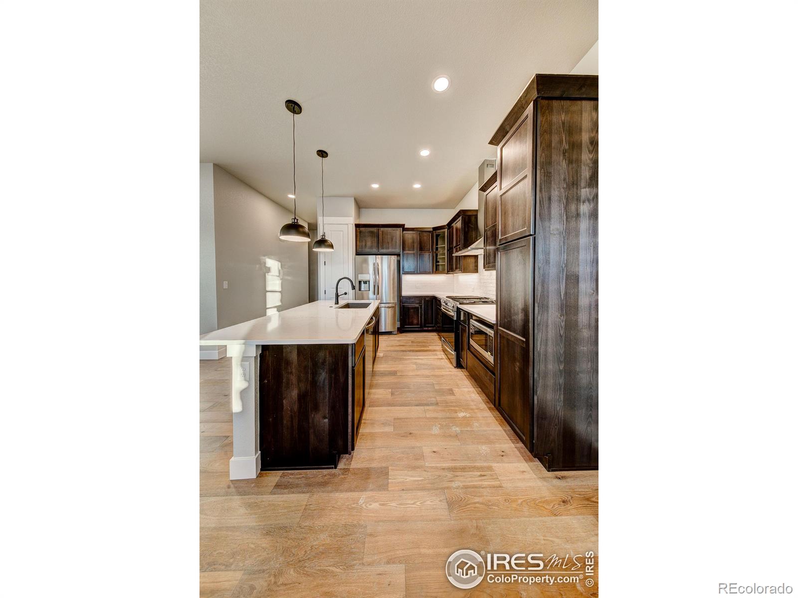 6227 Vernazza Way, Unit 4 Windsor, CO 80550 - Photo 3 of 15 a hallway with a large mirror and a refrigerator