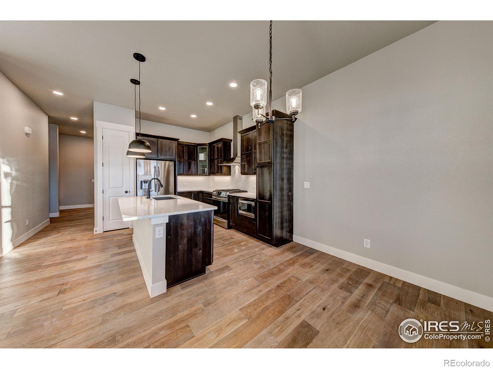 6227 Vernazza Way, Unit 4 Windsor, CO 80550 - Photo 5 of 15 a living room with kitchen island and a wooden floor