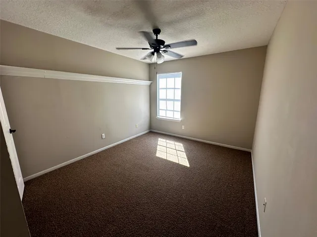 an empty room with a window and a ceiling fan