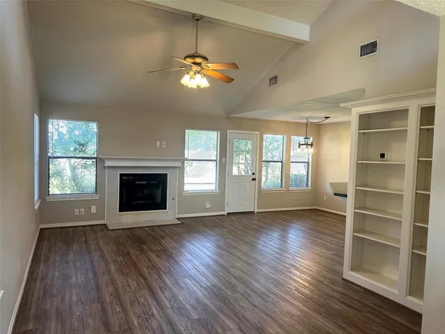 a view of an empty room with wooden floor fireplace and a window