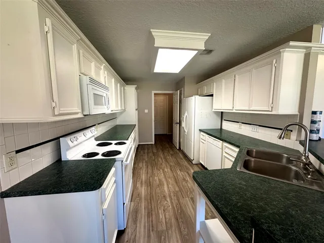 a kitchen with granite countertop a sink a stove and refrigerator