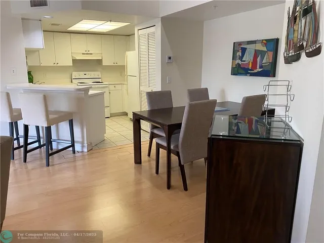 a kitchen with stainless steel appliances granite countertop a stove a refrigerator a dining table and chairs with wooden floor