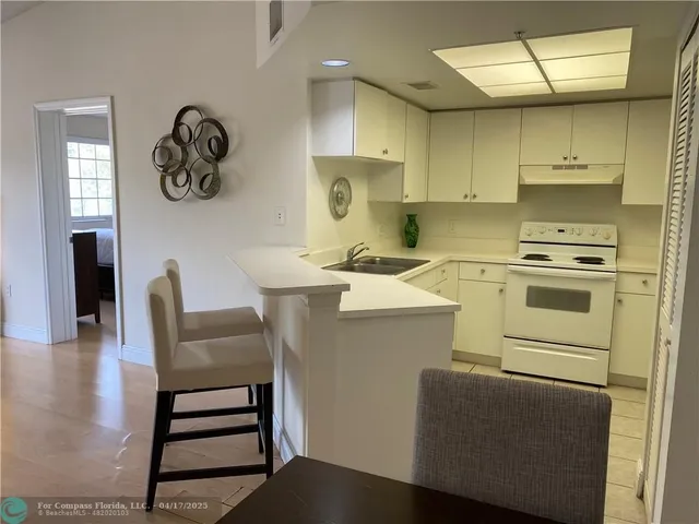 a kitchen with stainless steel appliances a stove a sink dishwasher and white cabinets with wooden floor