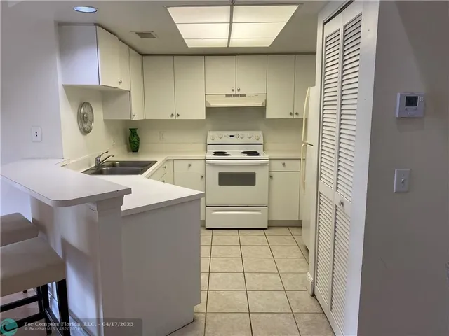 a kitchen with a stove a sink a refrigerator and cabinets
