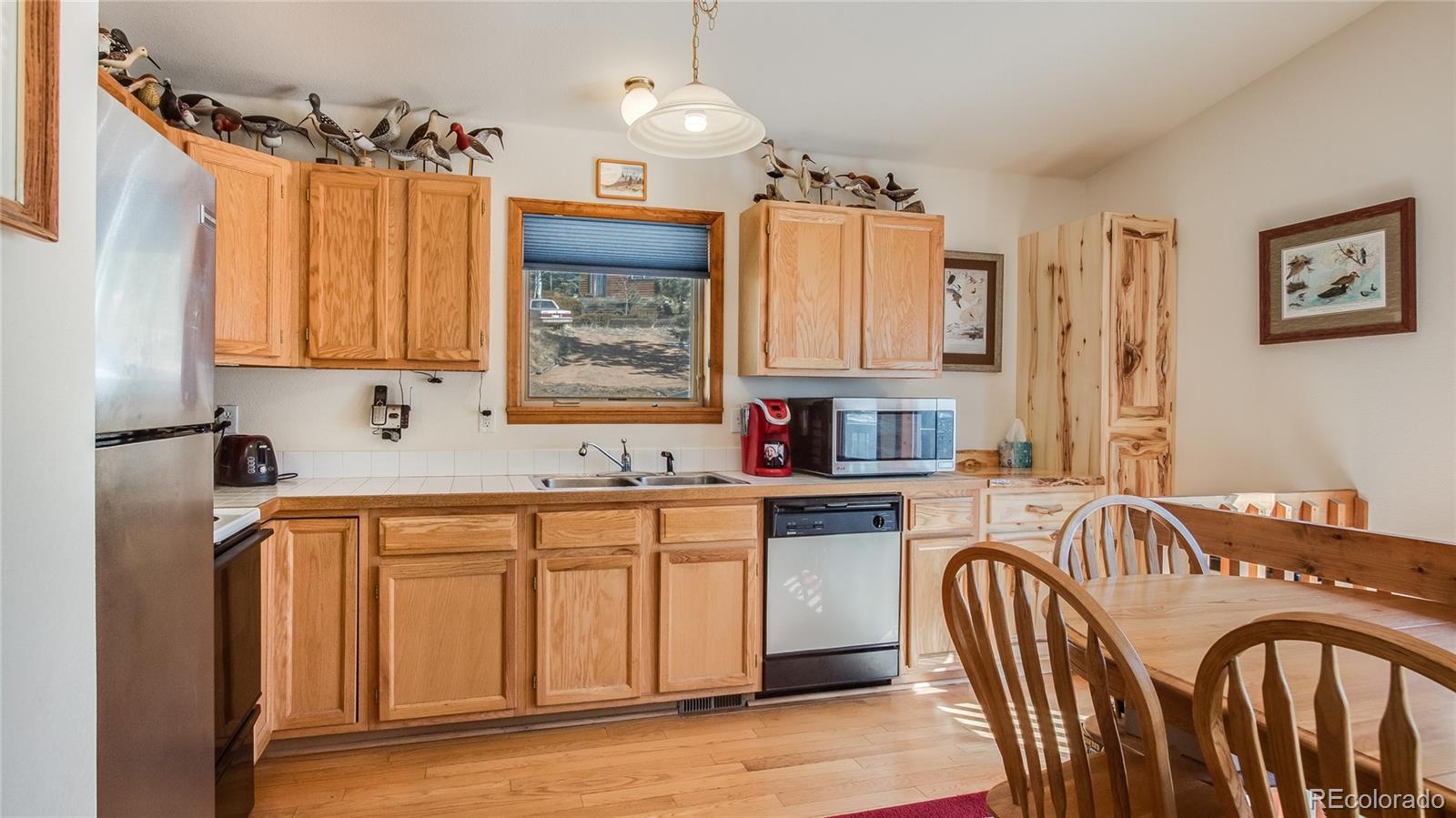 302 Bishop Road Bailey, CO 80421 - Photo 9 of 19 a kitchen with stainless steel appliances granite countertop a refrigerator a sink dishwasher a dining table and chairs with wooden floor