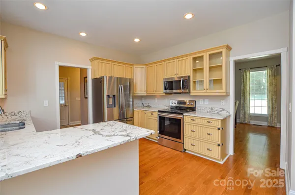 a large kitchen with kitchen island granite countertop a stove top oven a sink dishwasher a dining table and chairs with wooden floor