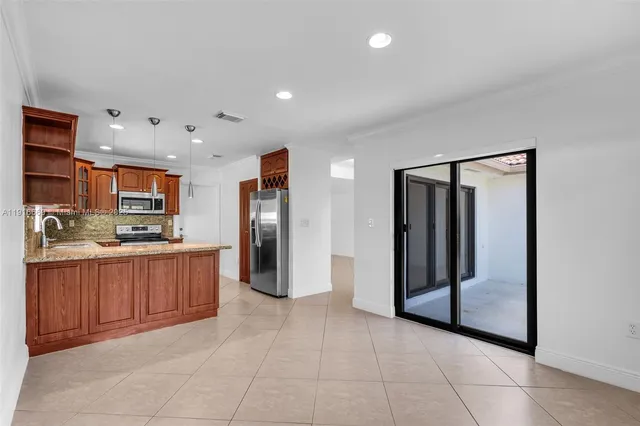 a large kitchen with stainless steel appliances kitchen island granite countertop a refrigerator and a sink